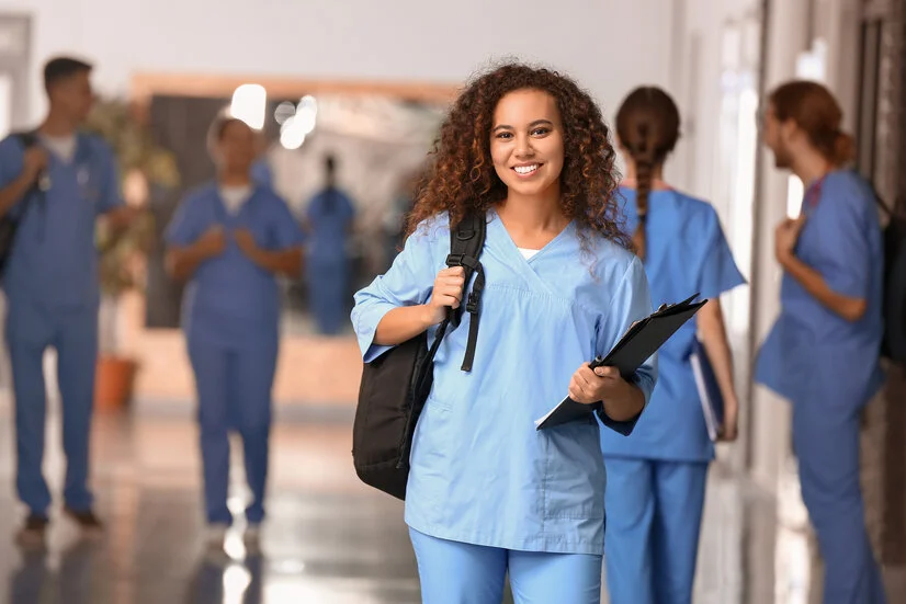 Junge Pflegekraft in blauer Uniform, lächelnd im Krankenhausflur